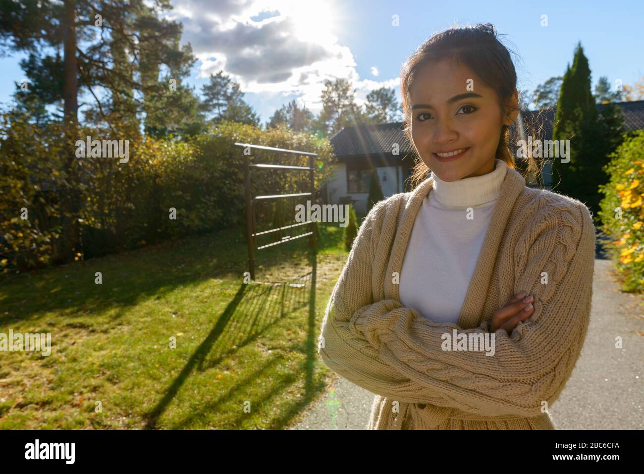 Felice giovane bella donna asiatica sorridente nel cortile anteriore Foto Stock
