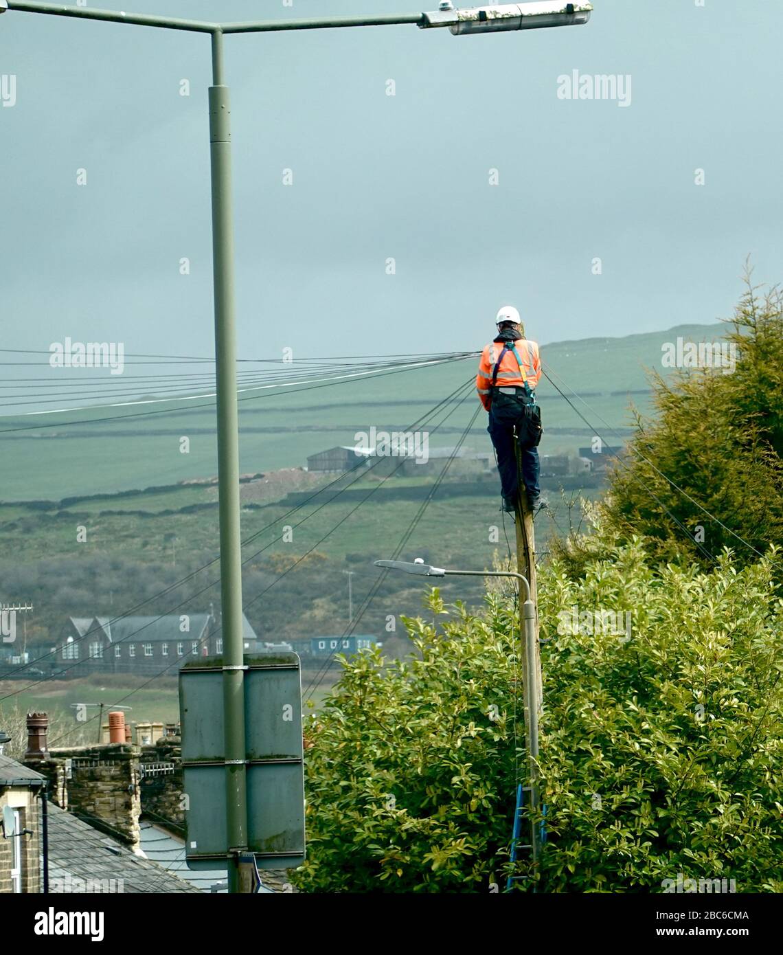 Un tecnico telefonico regola una linea telefonica su Spring Bank, New Mills, Derbyshire con Kinder Scout in background. Foto Stock