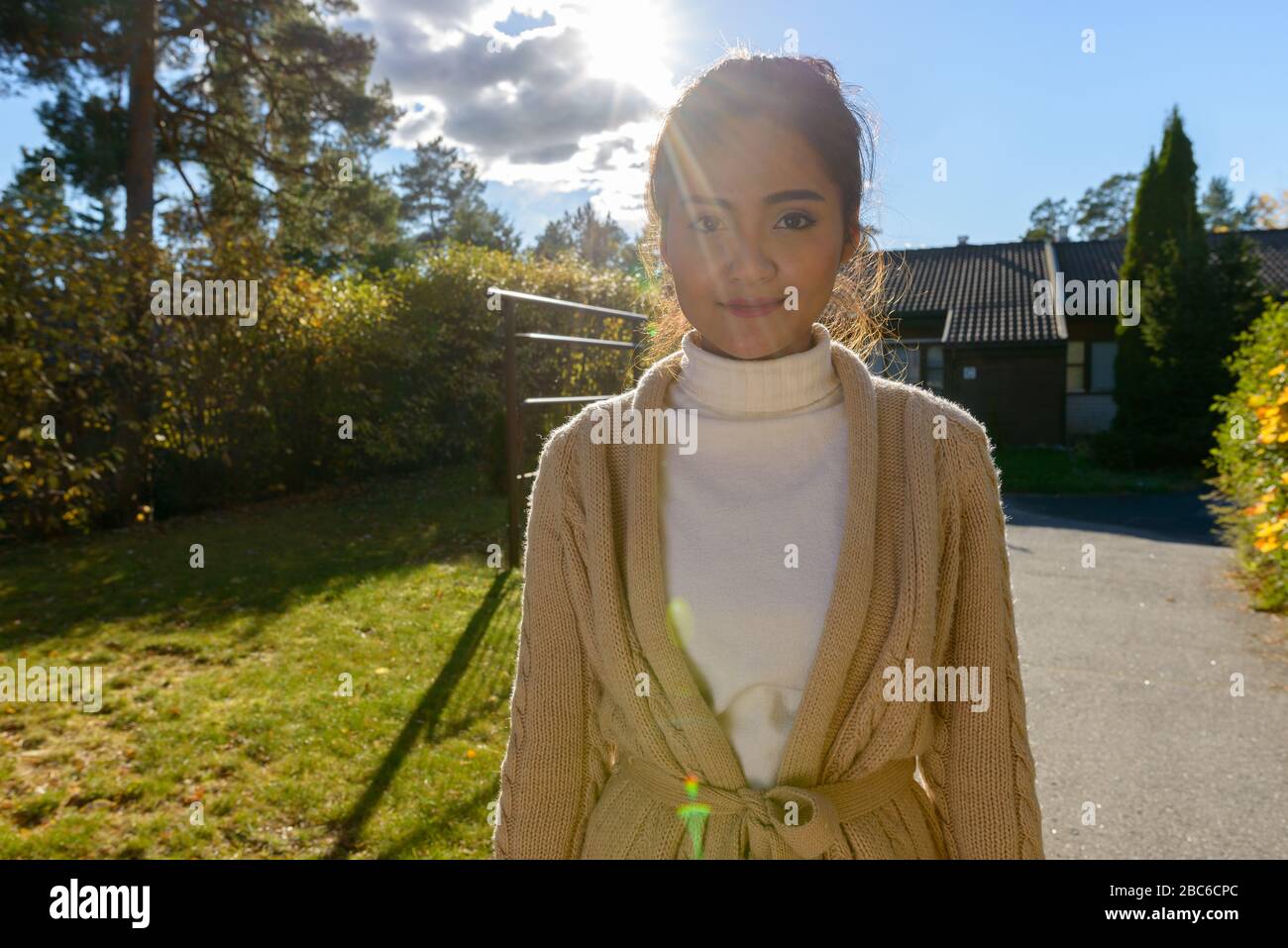 Giovane bella donna asiatica nel cortile anteriore a casa Foto Stock