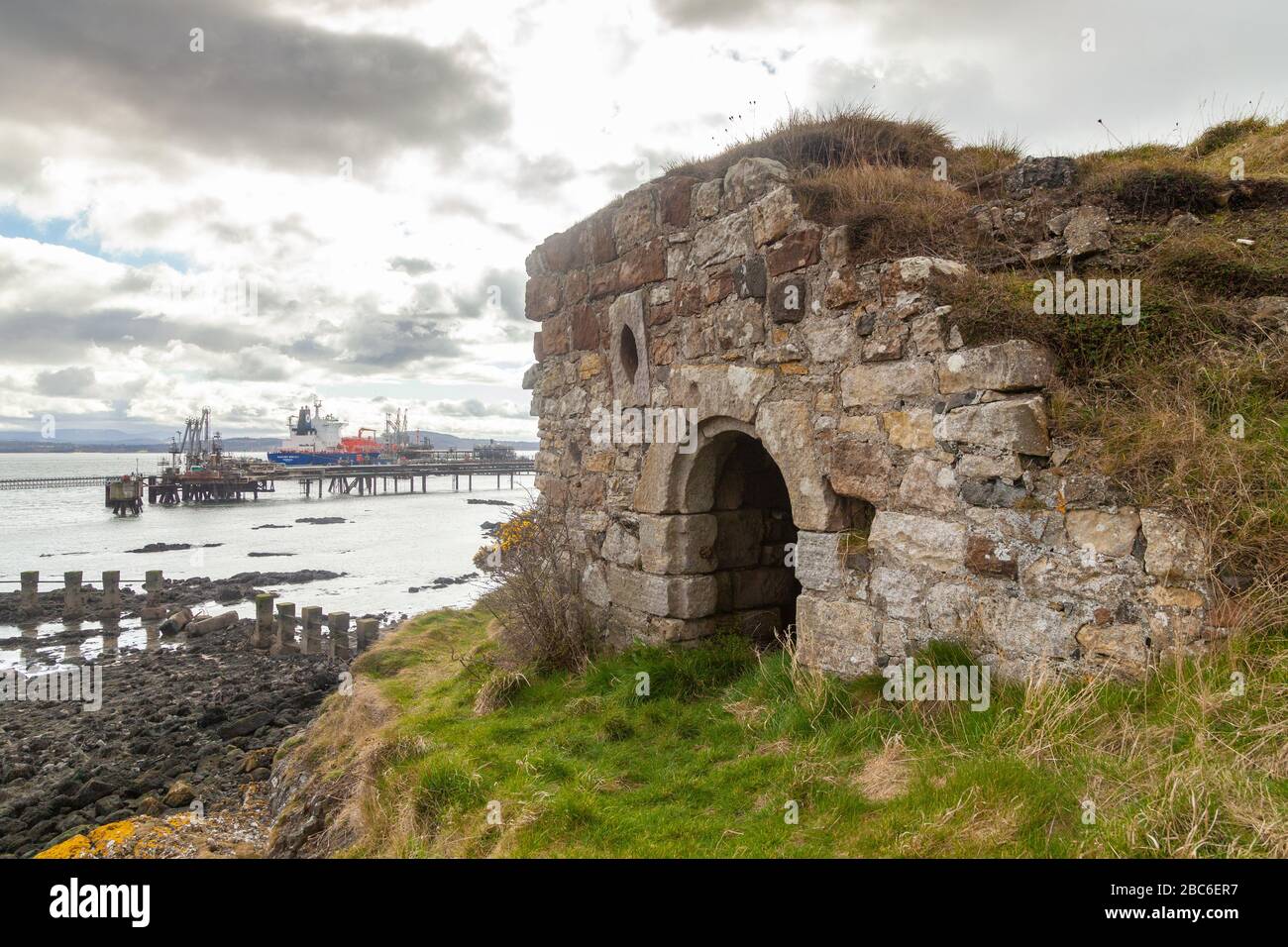 Monk's Cave con Braefoot Oil Terminal sullo sfondo, Dalgety Bay, Fife, Scozia. Foto Stock