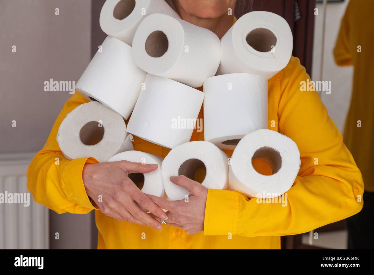 Una donna con un'armful di rotoli di toletta. Foto Stock