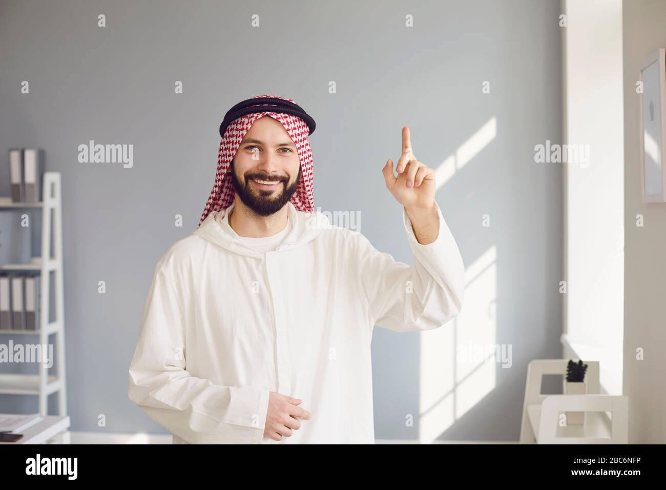 Allegro uomo arabo che indica in ufficio Foto Stock
