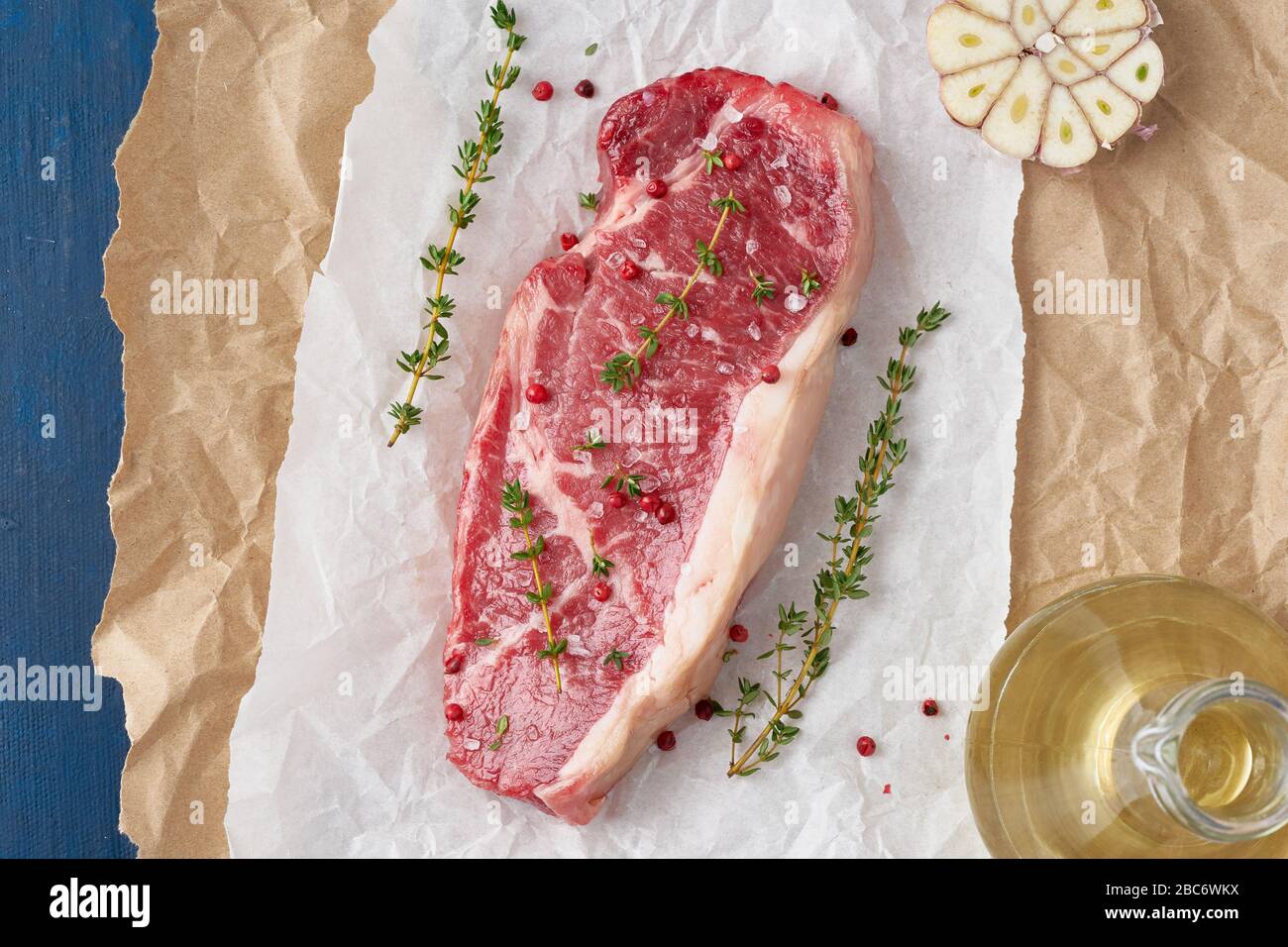 Grande pezzo intero di carne di manzo cruda, striploin su carta pergamena bianca Foto Stock