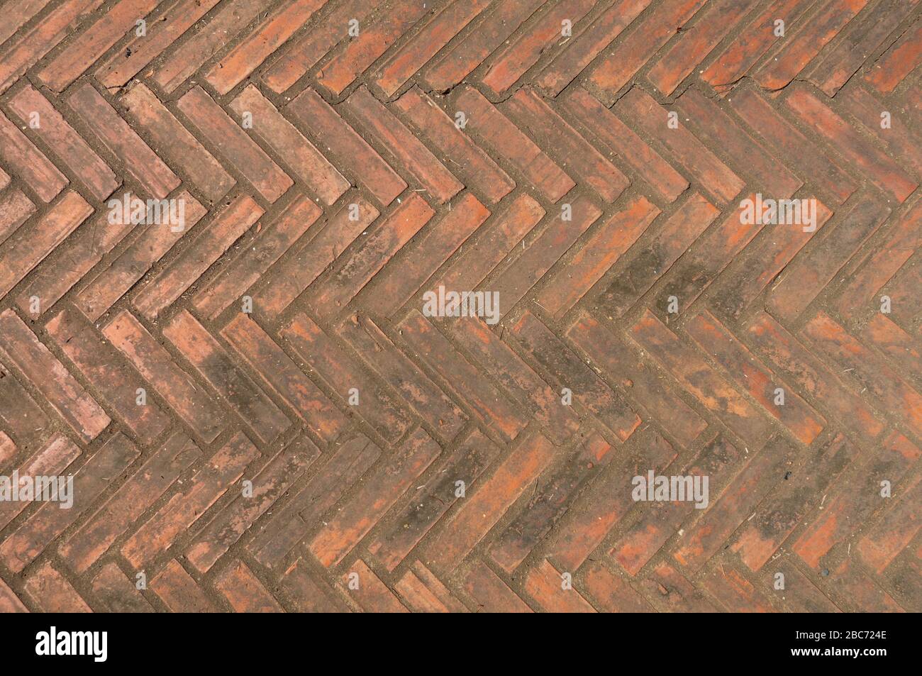 Parete e pavimento in mattoni, in motivo zigzag, astratto e sfondo, di colore marrone arancio. Foto Stock