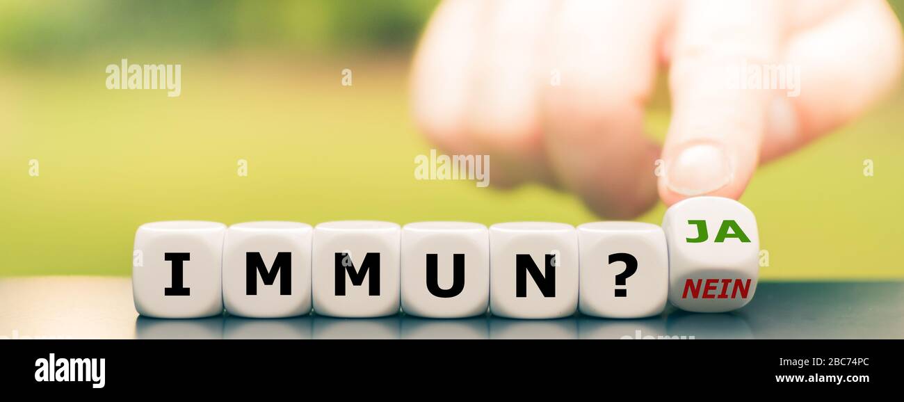 Corona immune? La mano gira i dadi e cambia l'espressione tedesca 'immun? nein ('immune? no') a 'immun? ja ('immune? sì"). Foto Stock