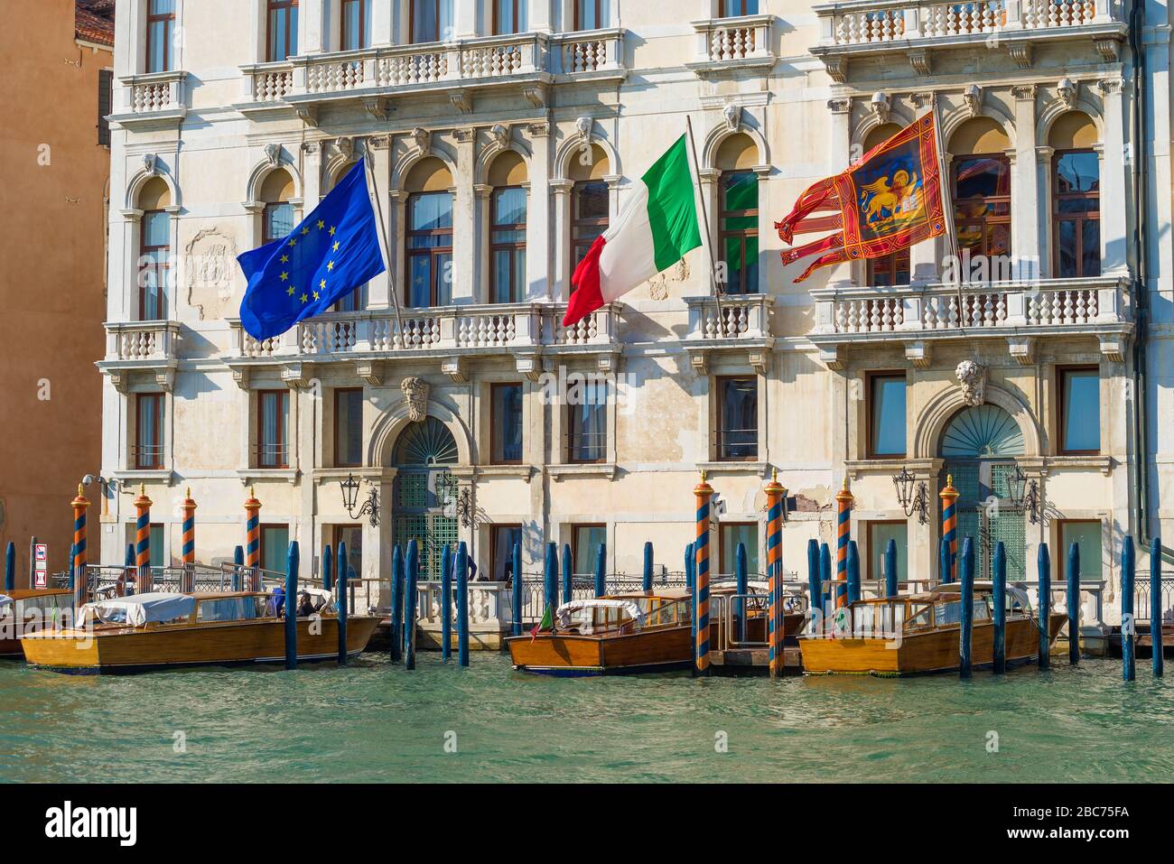 Bandiere dell'Unione europea, dell'Italia e di Venezia sulla facciata di un vecchio edificio in una giornata di sole. Venezia, Italia Foto Stock