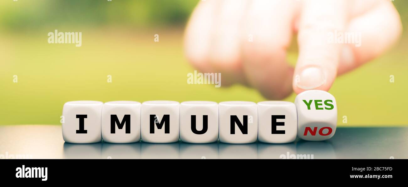 Corona immune? La mano gira i dadi e cambia l'espressione 'immune no' in 'immune sì'. Foto Stock