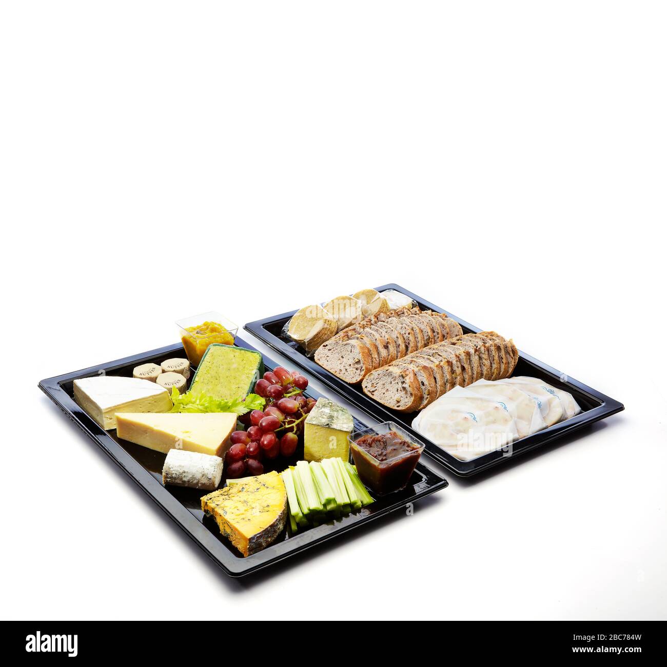 Frutta, pane, formaggio, prosciutto, torta in un vassoio per la colazione su sfondo bianco. Foto Stock