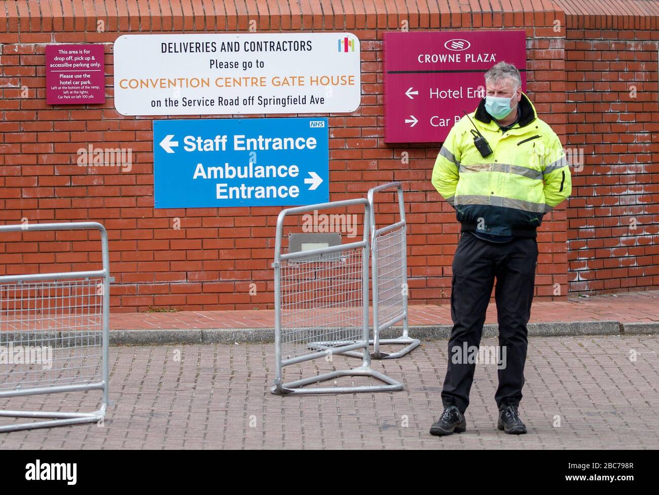 Una guardia di sicurezza che indossa un facemask al di fuori del centro convegni Harrogate, che viene convertito per accogliere fino a 500 pazienti dallo Yorkshire e dal nord-est dell'Inghilterra, mentre il Regno Unito continua a bloccarsi per contribuire a frenare la diffusione del coronavirus. Foto Stock
