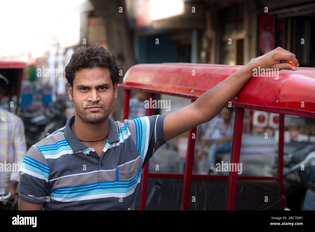 Ritratto di un pilota locale di rickshaw che posa accanto al suo veicolo a Jaipur, India Foto Stock