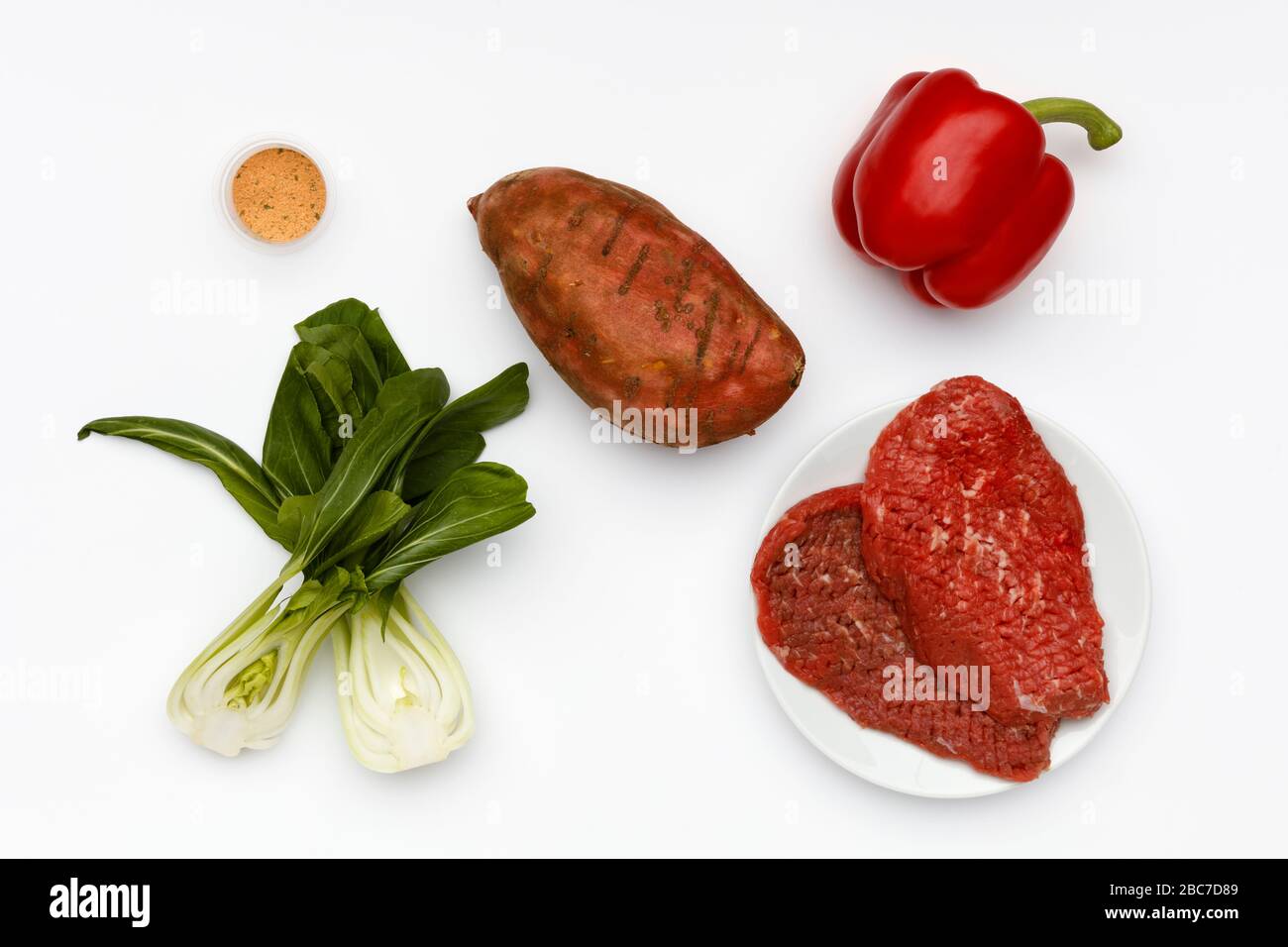 Ingredienti freschi per la produzione di carne di manzo al cajun, con verdure e spezie su uno sfondo bianco brillante Foto Stock