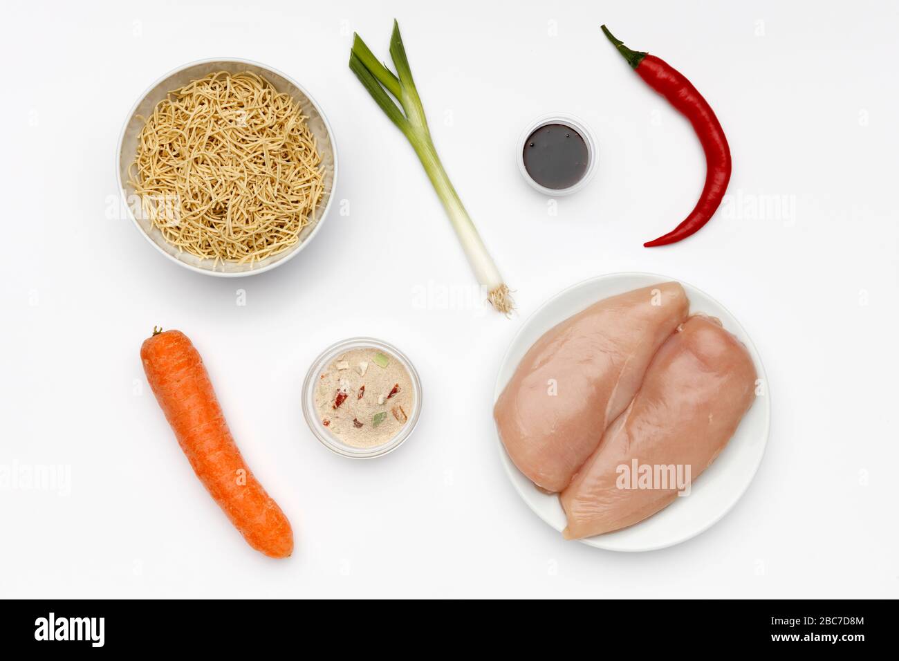 Ingredienti freschi per preparare il mein di pollo, con verdure e tagliatelle su uno sfondo bianco brillante Foto Stock