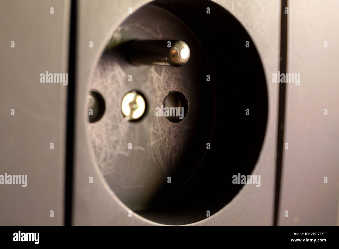 Un ritratto ravvicinato di una presa a muro di tipo e utilizzata per alimentare dispositivi elettrici o elettronici. Ha due fori e una messa a terra o messa a terra. IT Foto Stock