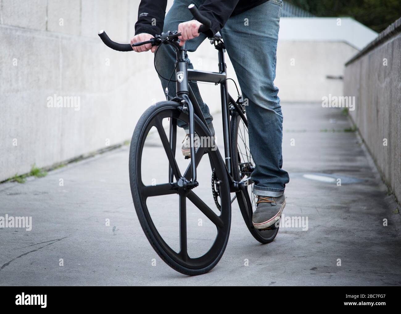 Uomo che guida una moto a velocità singola in un ambiente urbano Foto Stock
