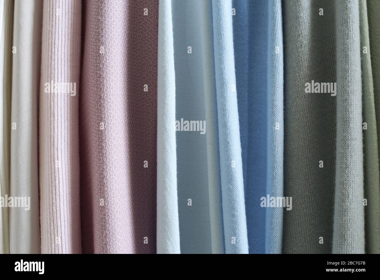 Mix colorato e pattern appeso a strisce verticali, tessuti, panni sul rack. Mix di colore pastello del tessuto. Foto Stock