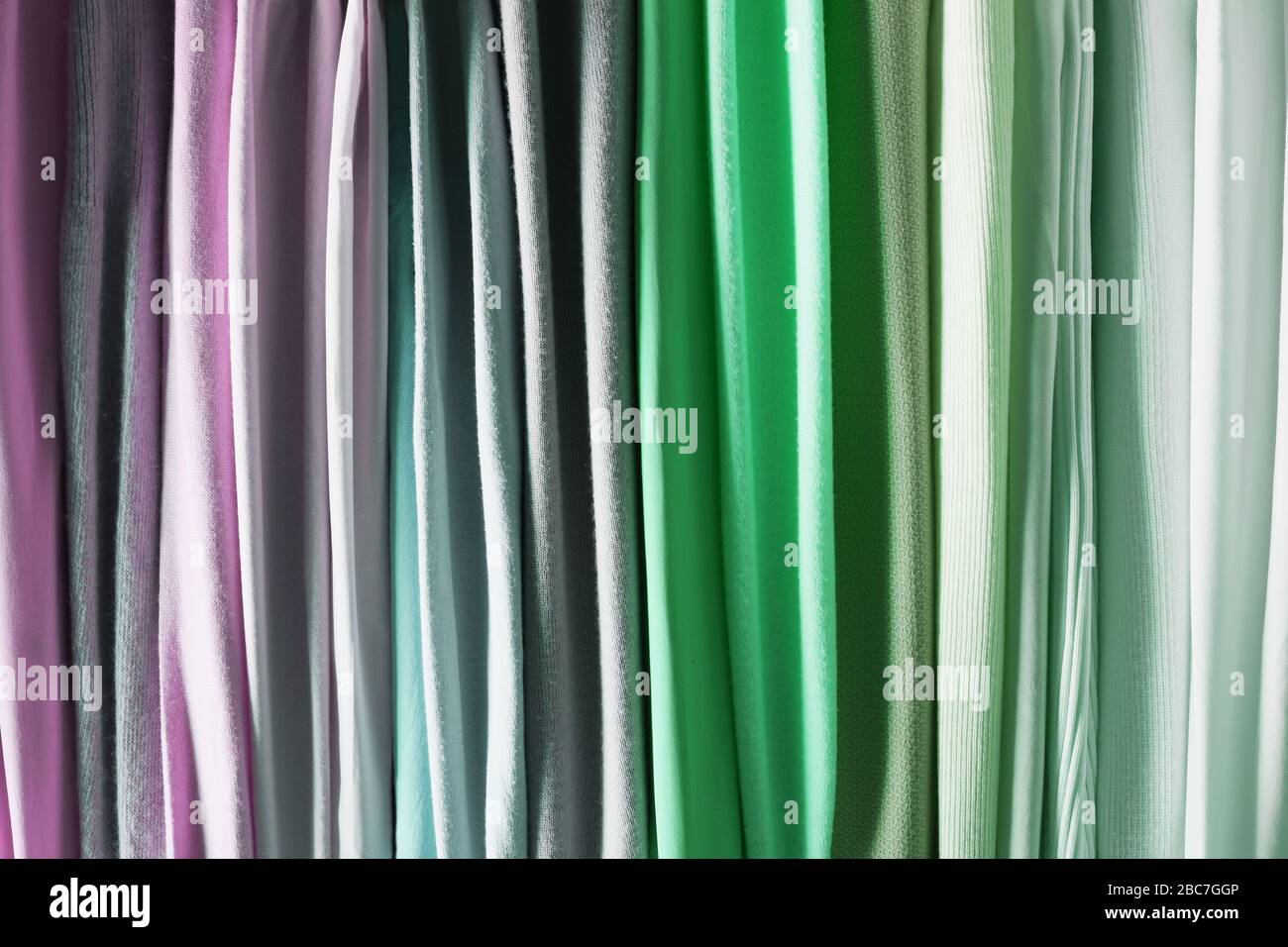 Mix colorato e pattern appeso a strisce verticali, tessuti, panni sul rack. Mix di colore pastello del tessuto. Foto Stock
