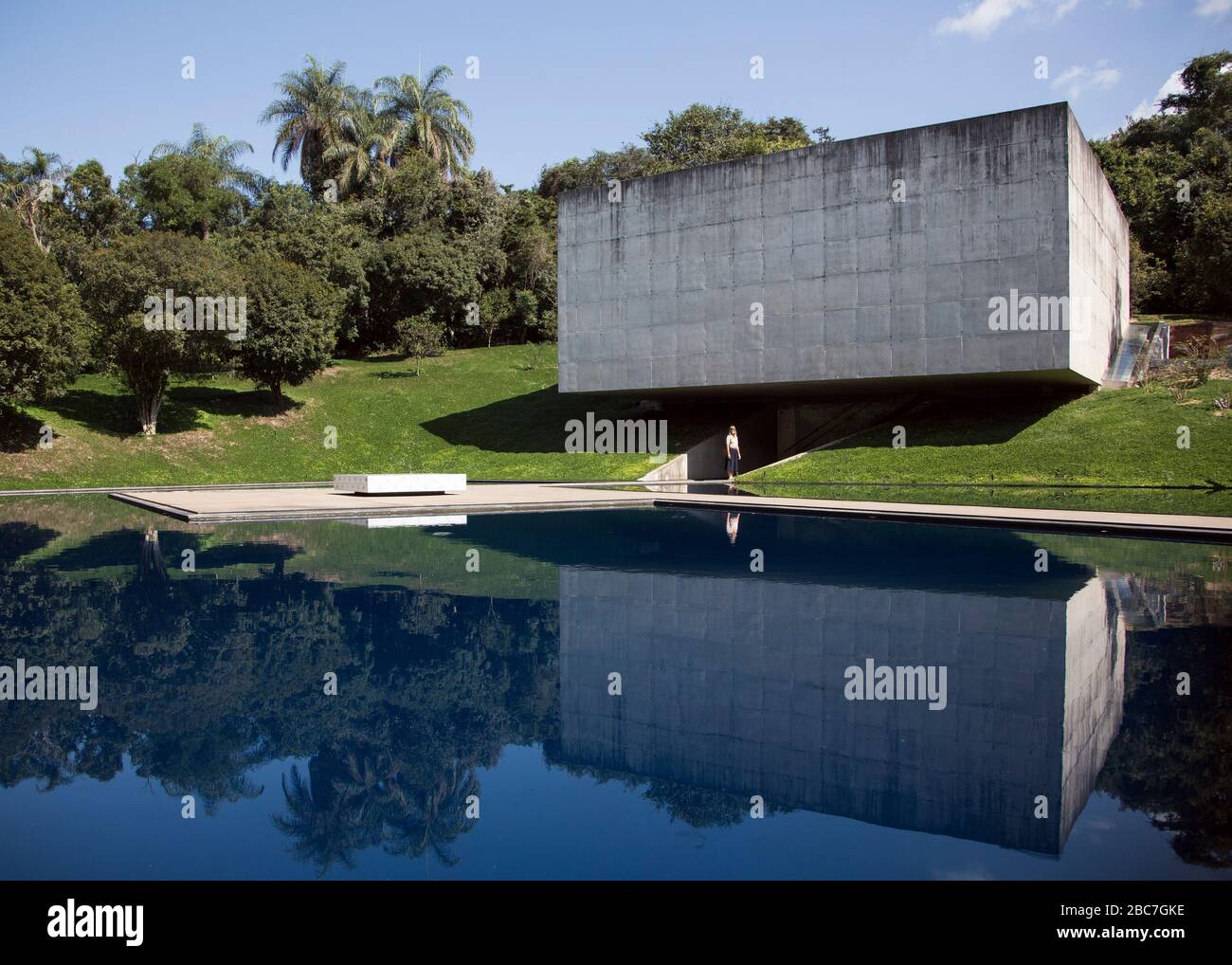 Una donna si trova di fronte a uno dei numerosi edifici che ospitano l'arte a Inhotim l'Istituto di Arte Contemporanea e Giardini Botanici in Brasile. Foto Stock