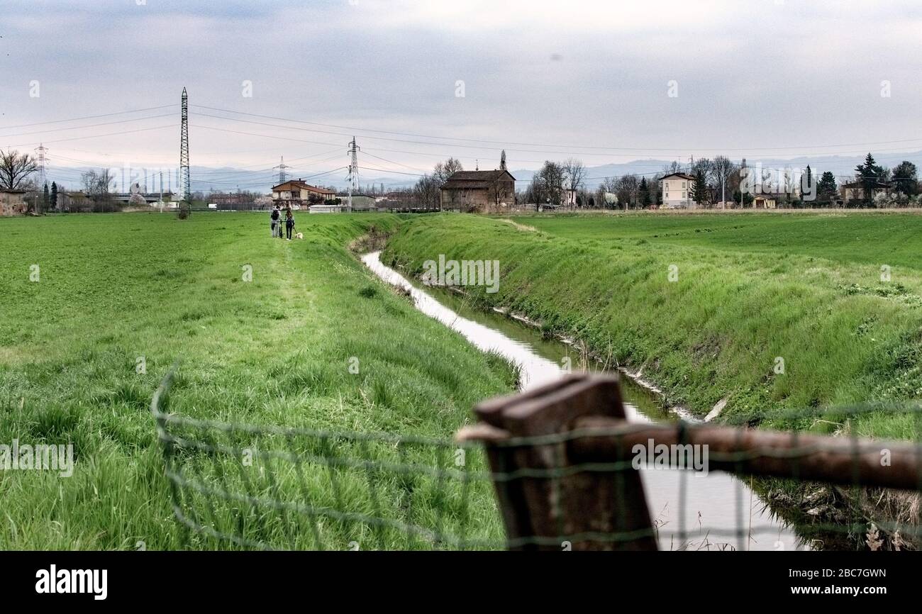 Una coppia che cammina in un campo con un dio vicino a un vapore / fiume Foto Stock