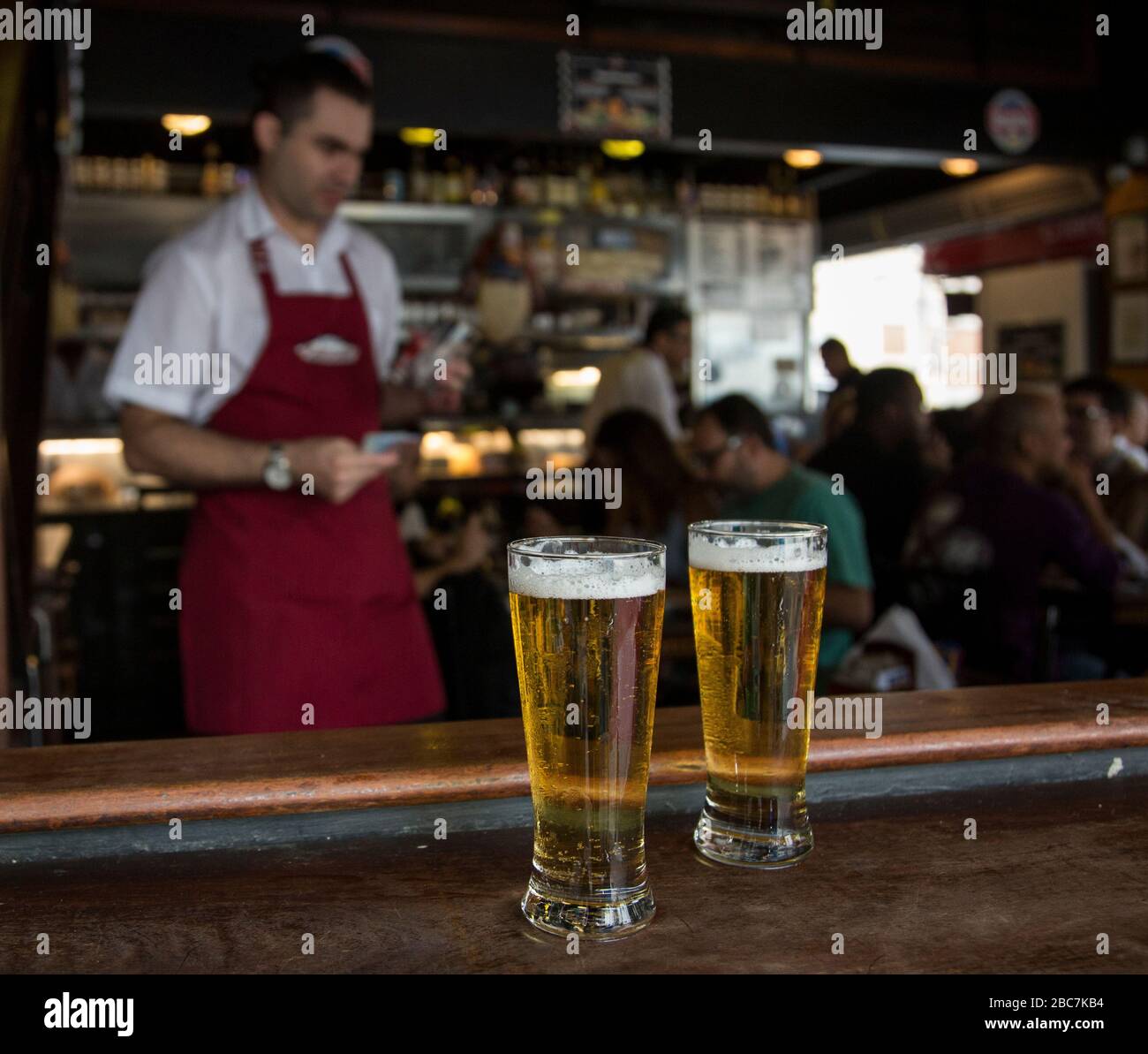 Piccole birre al bar con un bar tenero e persone sullo sfondo Foto Stock