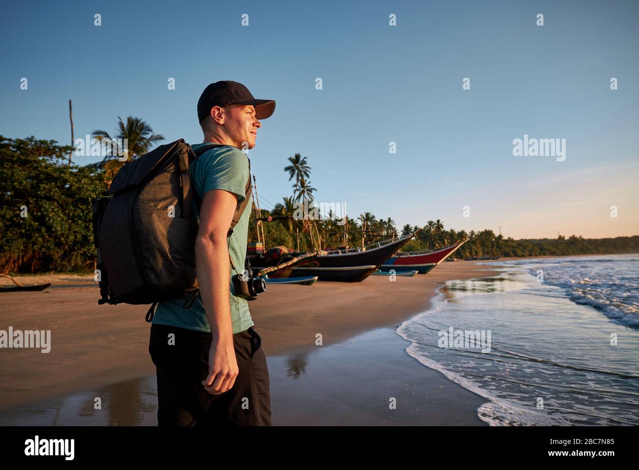 Giovane uomo con zaino a piedi su spiaggia di sabbia tropicale. Costa dello Sri Lanka al semaforo del mattino. Foto Stock