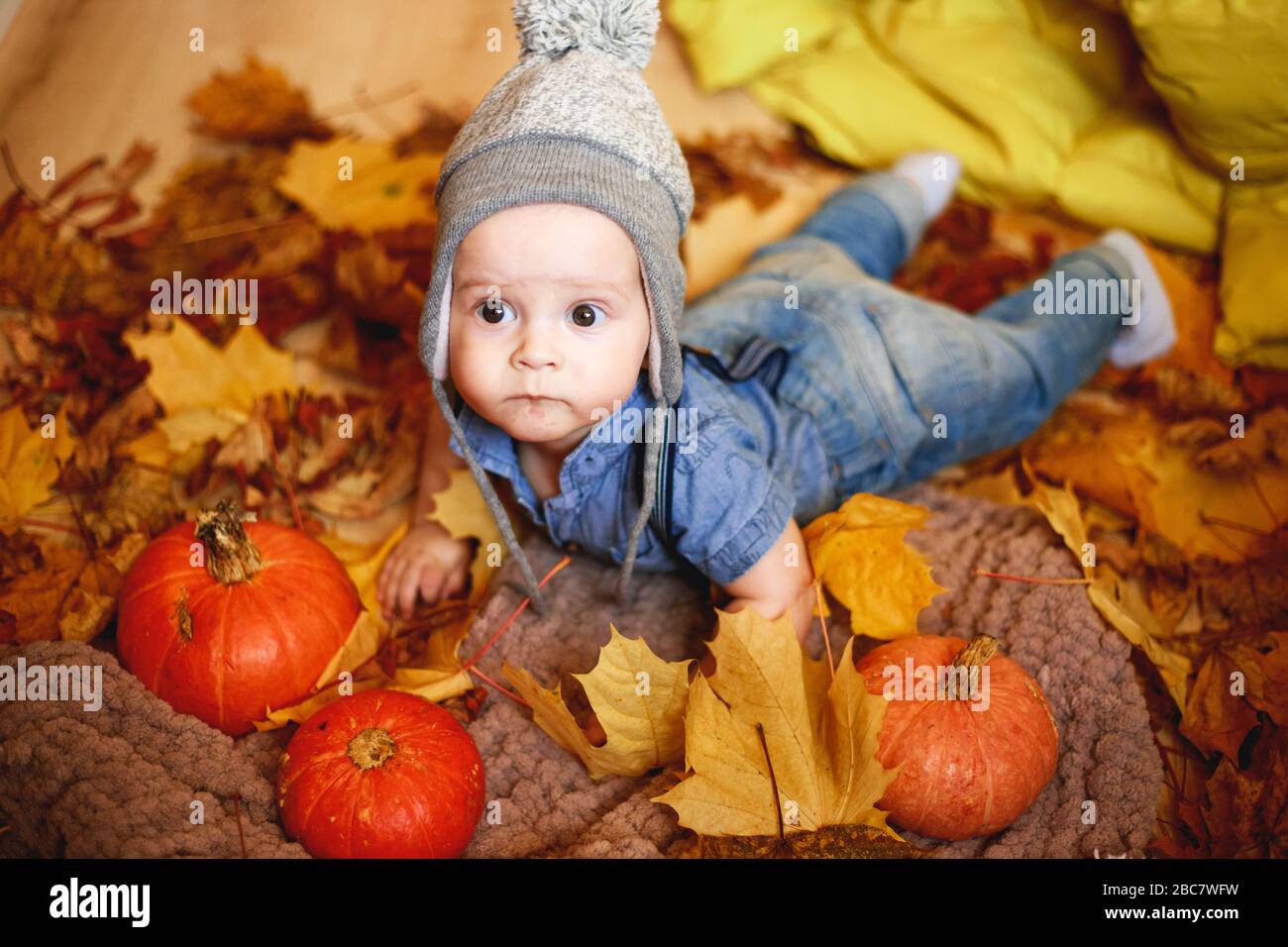 un ragazzino gioca in autunno lascia accanto alle zucche. foto dai colori caldi Foto Stock