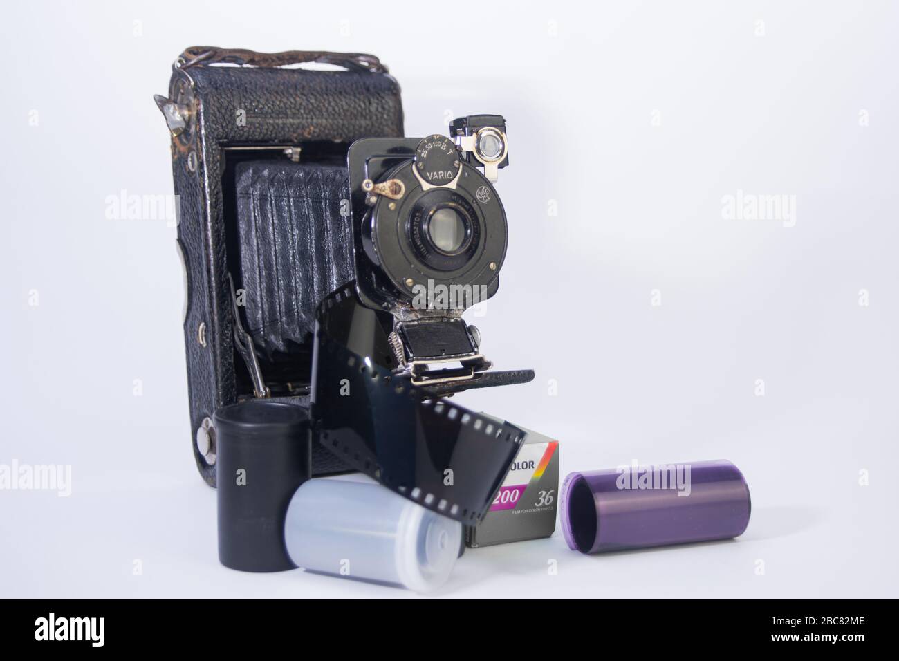 vecchia scuola fotocamera da 35 mm, e obiettivi per fotocamera con contenitori di pellicola e nastri di pellicola intorno isolato su sfondo bianco Foto Stock