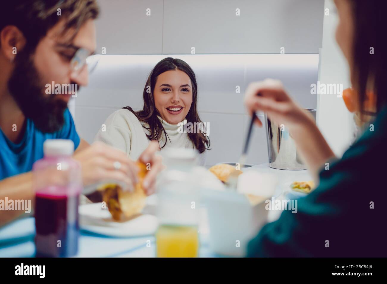 Bella ragazza bruna sorridente e parlare mentre pranzare con gli amici Foto Stock