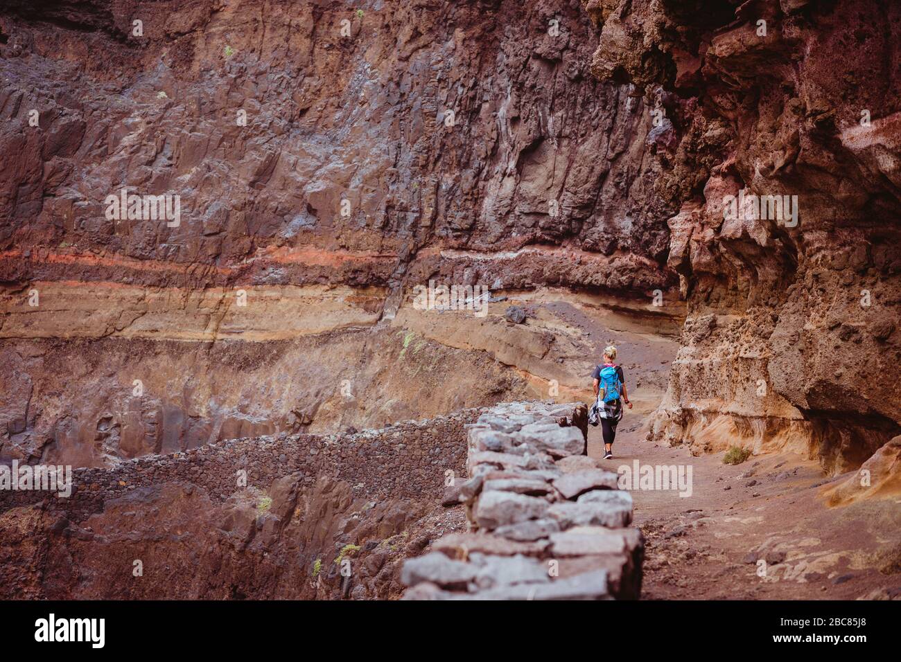 Le donne turistiche camminano lungo senso lungo la scogliera e costa pericolosa rocciosa da Cruzinha a Ponta do Sol. Enormi mura di montagna sono sul sentiero di trekking. San Foto Stock