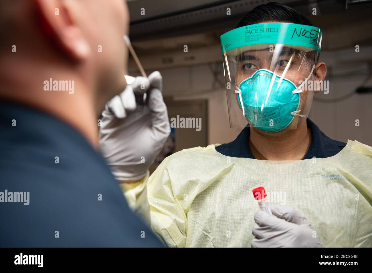 U.S. Navy Hospital Corpsman 2nd Classe Adrian Noceda, prende un campione di tampone per i test COVID-19 a bordo del vettore aereo USS Theodore Roosevelt 27 marzo 2020 a Apra Harbour, Guam. Il comandante delle navi, Capt Brett Crozier, è stato sollevato dal dazio il 31 marzo 2020 dopo aver chiesto di intervenire per contribuire a arginare la diffusione dei casi COVID-19 sulla sua nave. Foto Stock