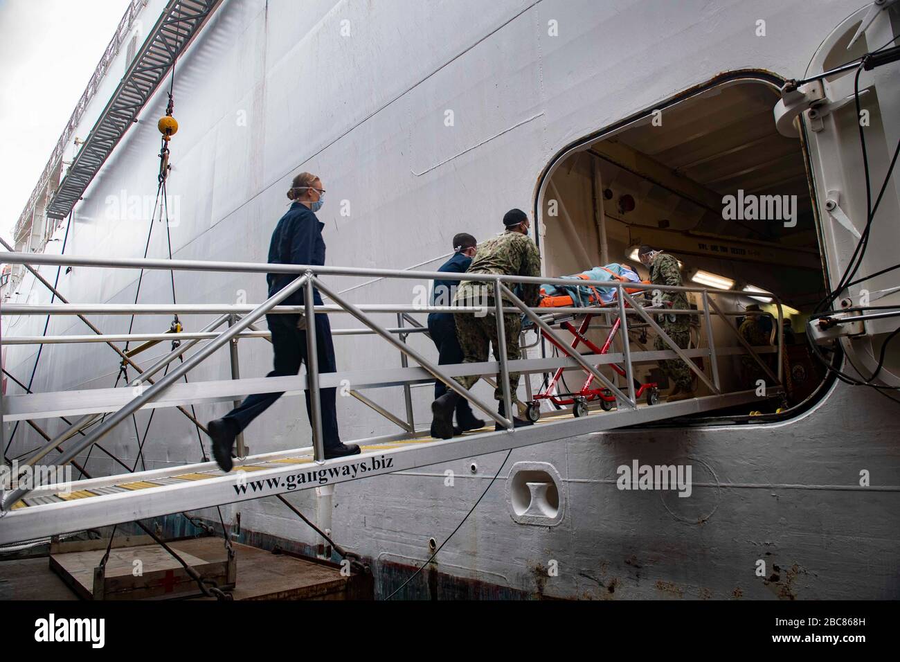 I marinai della Marina statunitense trasferiscono un paziente a bordo della nave dell'ospedale USNS Mercy schierato a sostegno del COVID-19, Coronavirus pandemic 1 aprile 2020 a Los Angeles, California. Foto Stock