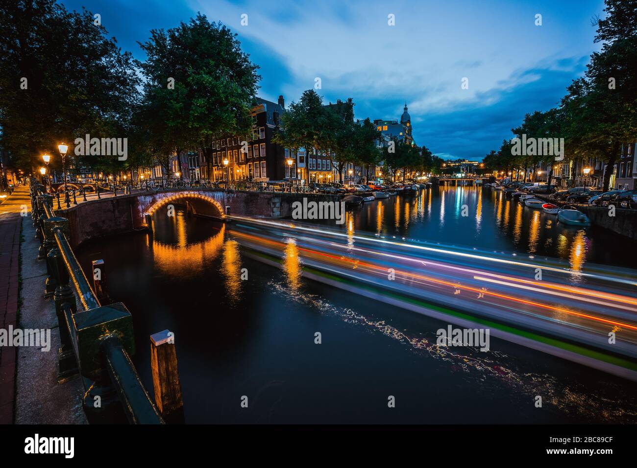 Notte a Amsterdam. Luci sentieri e ponti illuminati sul canale della città al crepuscolo. Holland, Paesi Bassi. Lunga esposizione. Foto Stock
