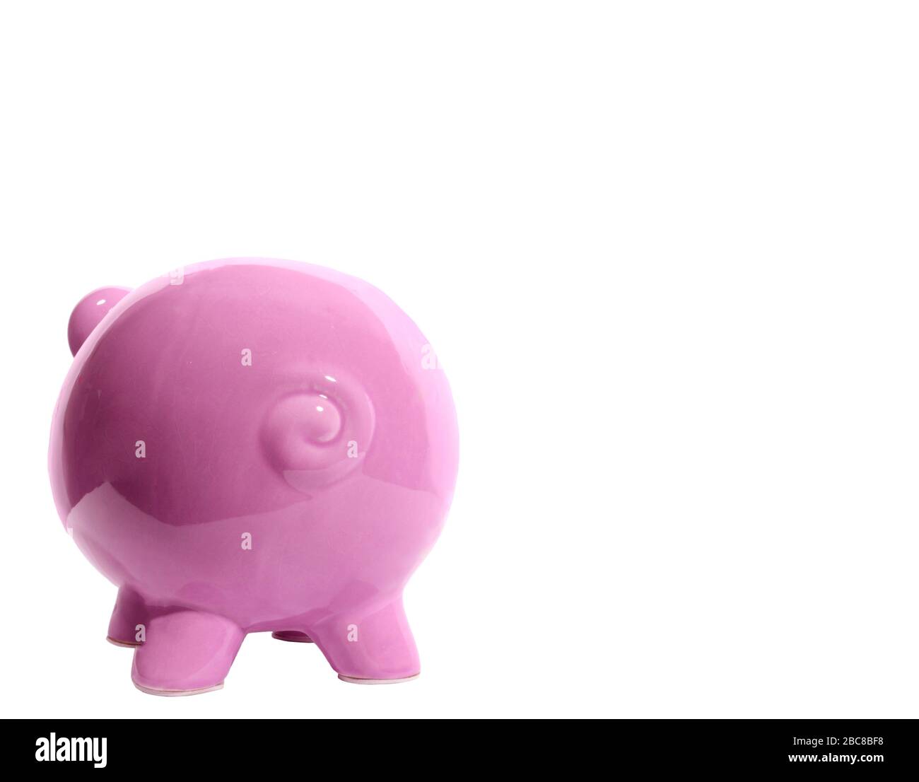 Scatto orizzontale di una banca rosa piggy che si affaccia lontano dalla fotocamera sul lato sinistro dell'immagine. Coda arricciata. Un sacco di spazio di copia sul lato destro. Foto Stock