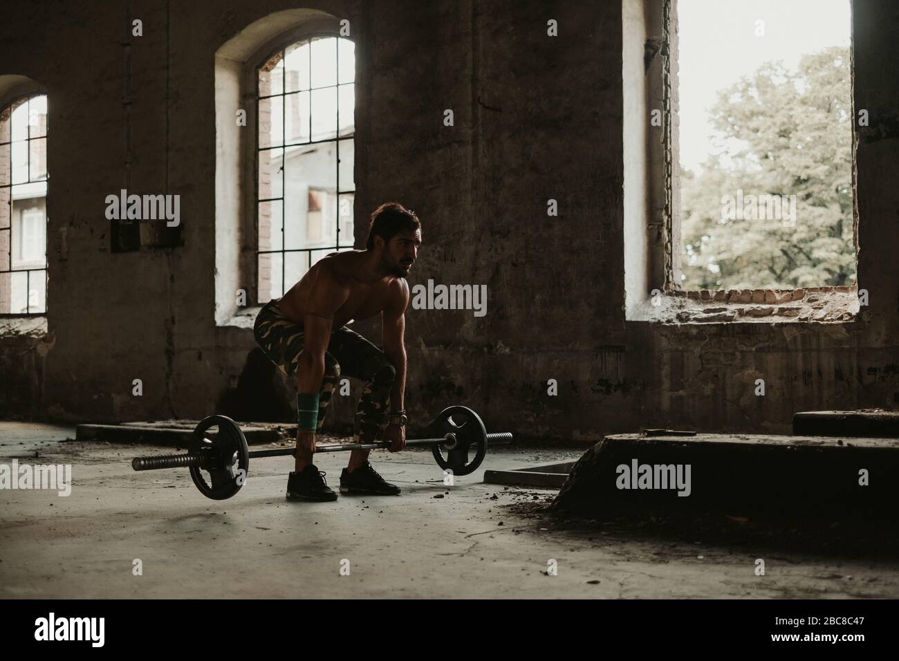 Uomo atletico barbuto che fa deadlift in un vecchio edificio. Bella giornata Foto Stock