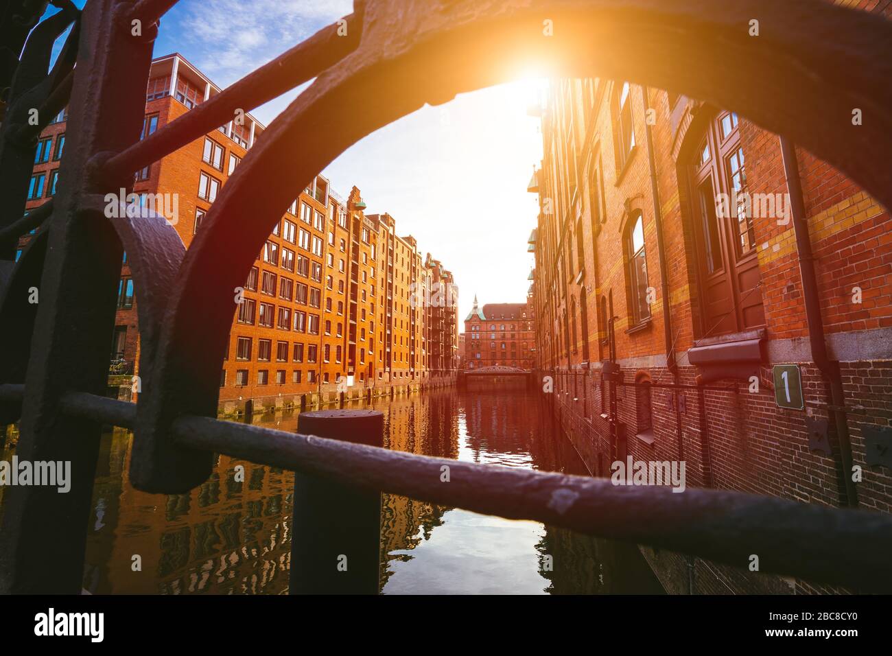 Speicherstadt di Amburgo. Famoso punto di riferimento di vecchi edifici costruiti con mattoni rossi. Ponte e raggi del sole in basso angolo di visione. Foto Stock