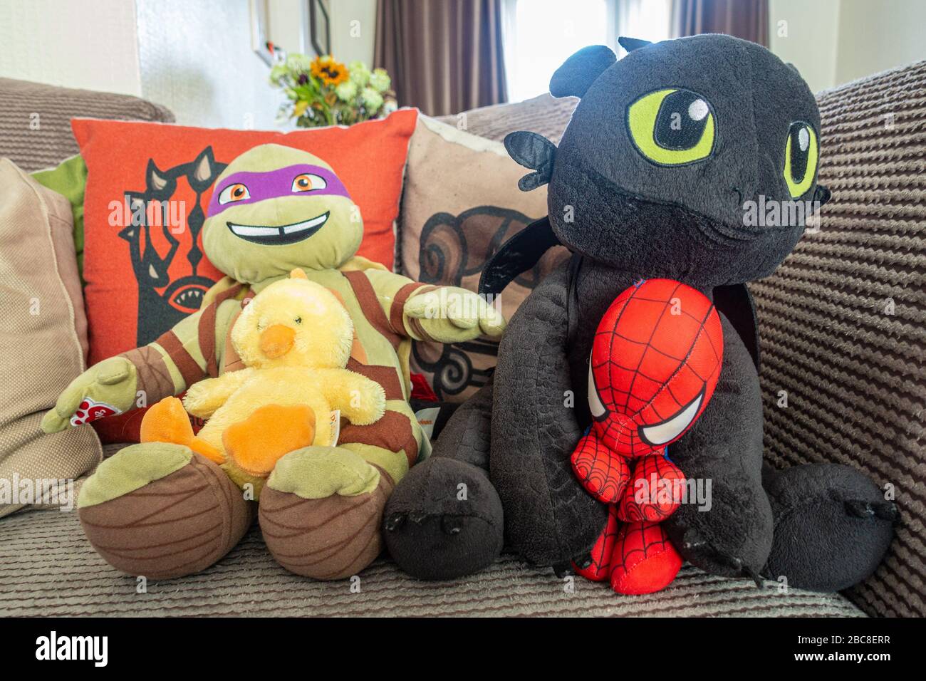 I giocattoli cudddddly assomigliano ai vari caratteri del cartone animato allineati lungo un settee. Foto Stock