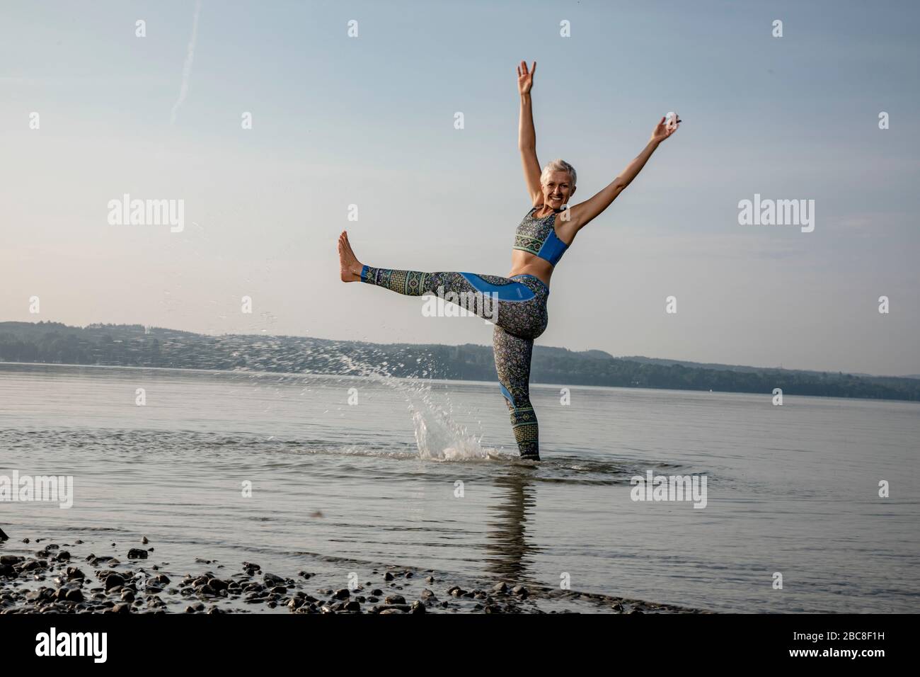 Meditazione IKYA, donna in abbigliamento sportivo allegramente sul lago Foto Stock