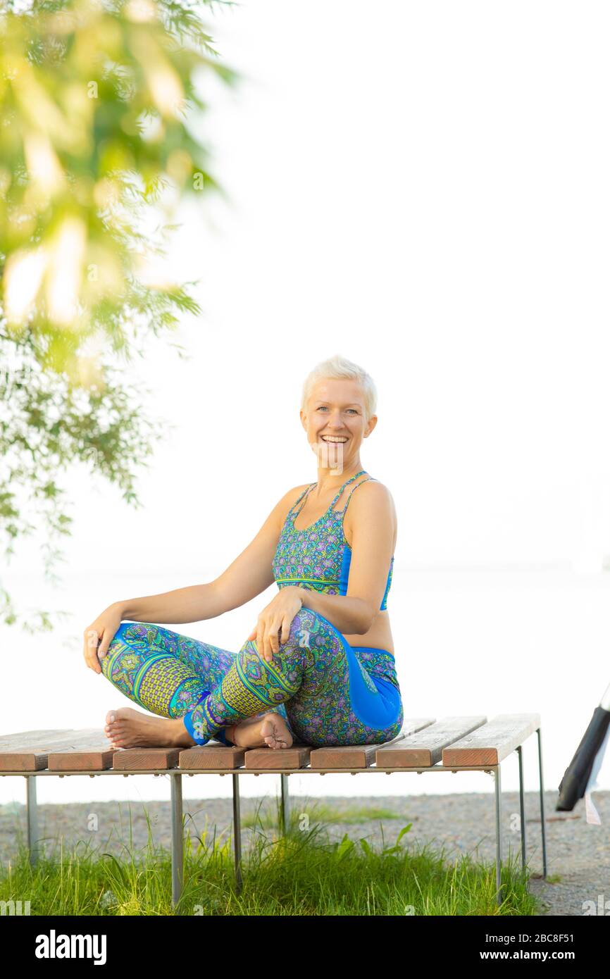 Meditazione IKYA, donna in abbigliamento sportivo allegramente sul lago Foto Stock