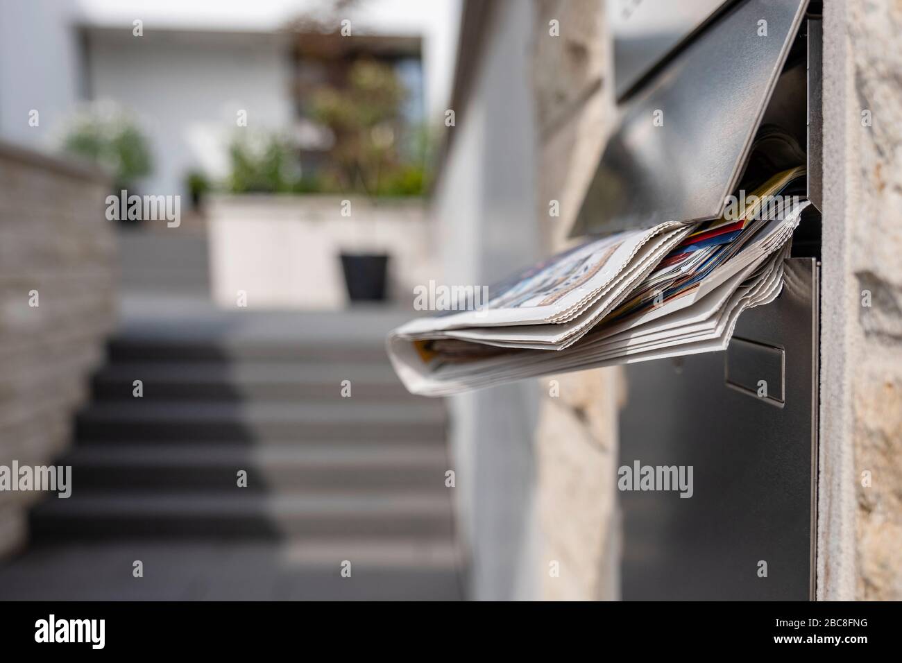 Casella postale piena di una casa di famiglia con un quotidiano con gli edifici in background Foto Stock