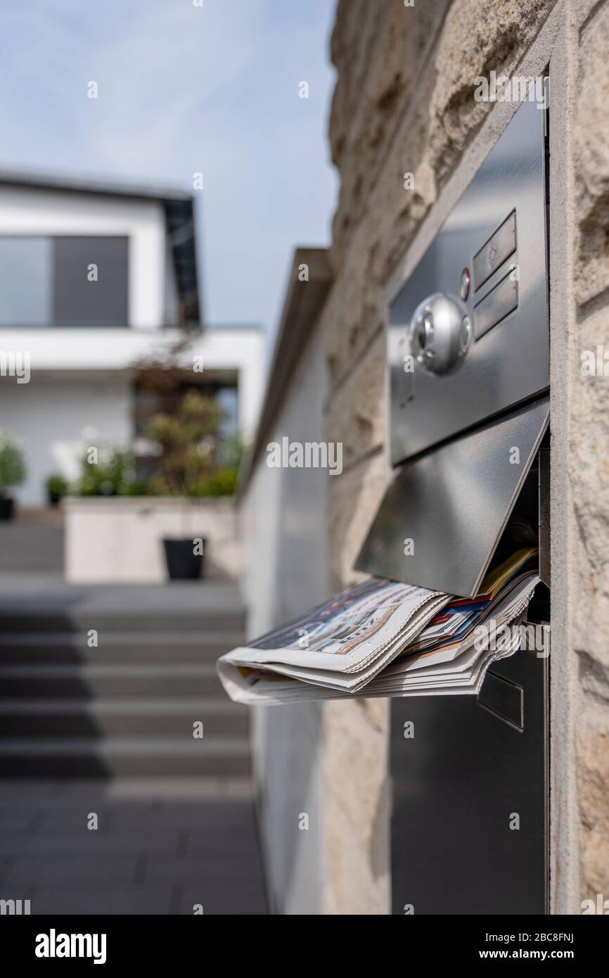 Casella postale piena di una casa di famiglia con un quotidiano con gli edifici in background Foto Stock