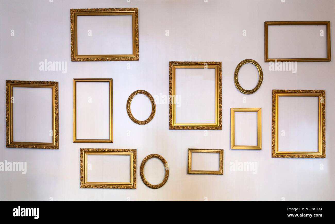 un muro in una stanza vuota con cornici d'arte vuote di diverse dimensioni Foto Stock
