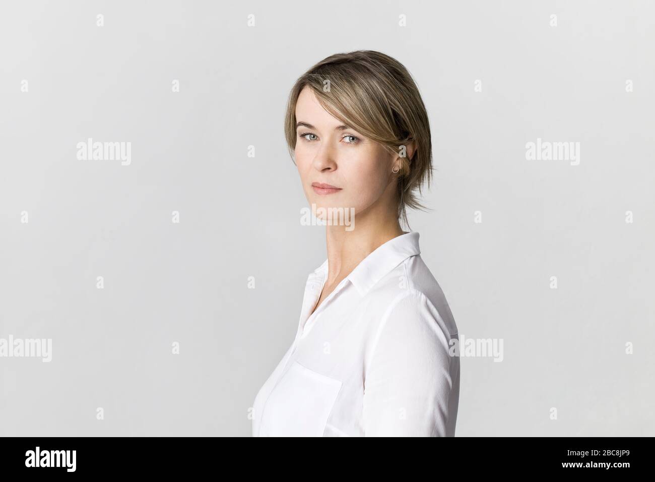 Imprenditrice ritratto in studio. La fiducia della donna in maglia bianca isolata su bianco Foto Stock