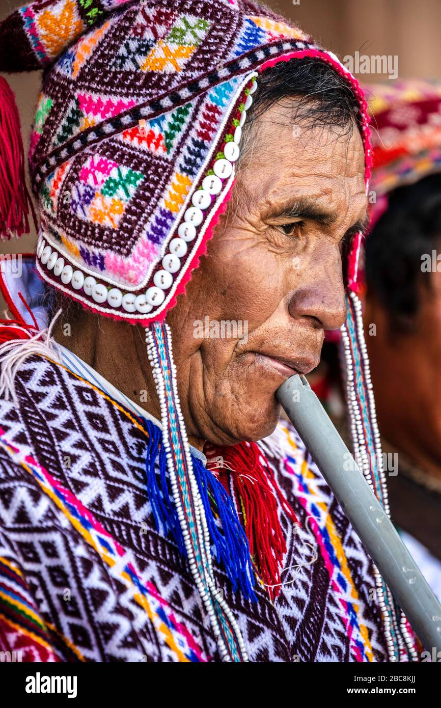 Quechua uomo indossando costume tradizionale (compreso il chullo) e suonando flauto, Pisac Domenica mercato, Pisac, Perù Foto Stock