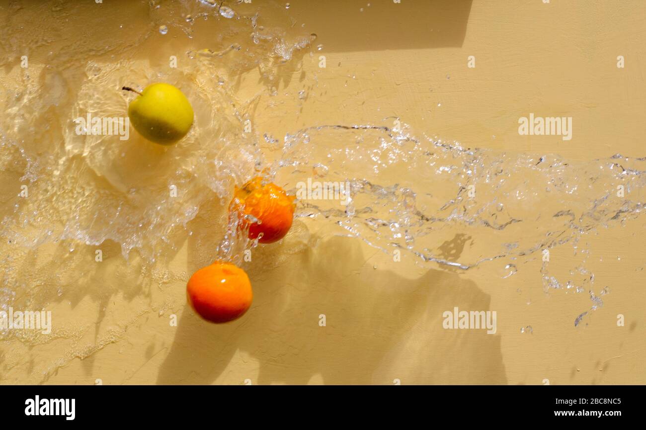 Banana, arancio, mela che volano in gocce d'acqua Foto Stock