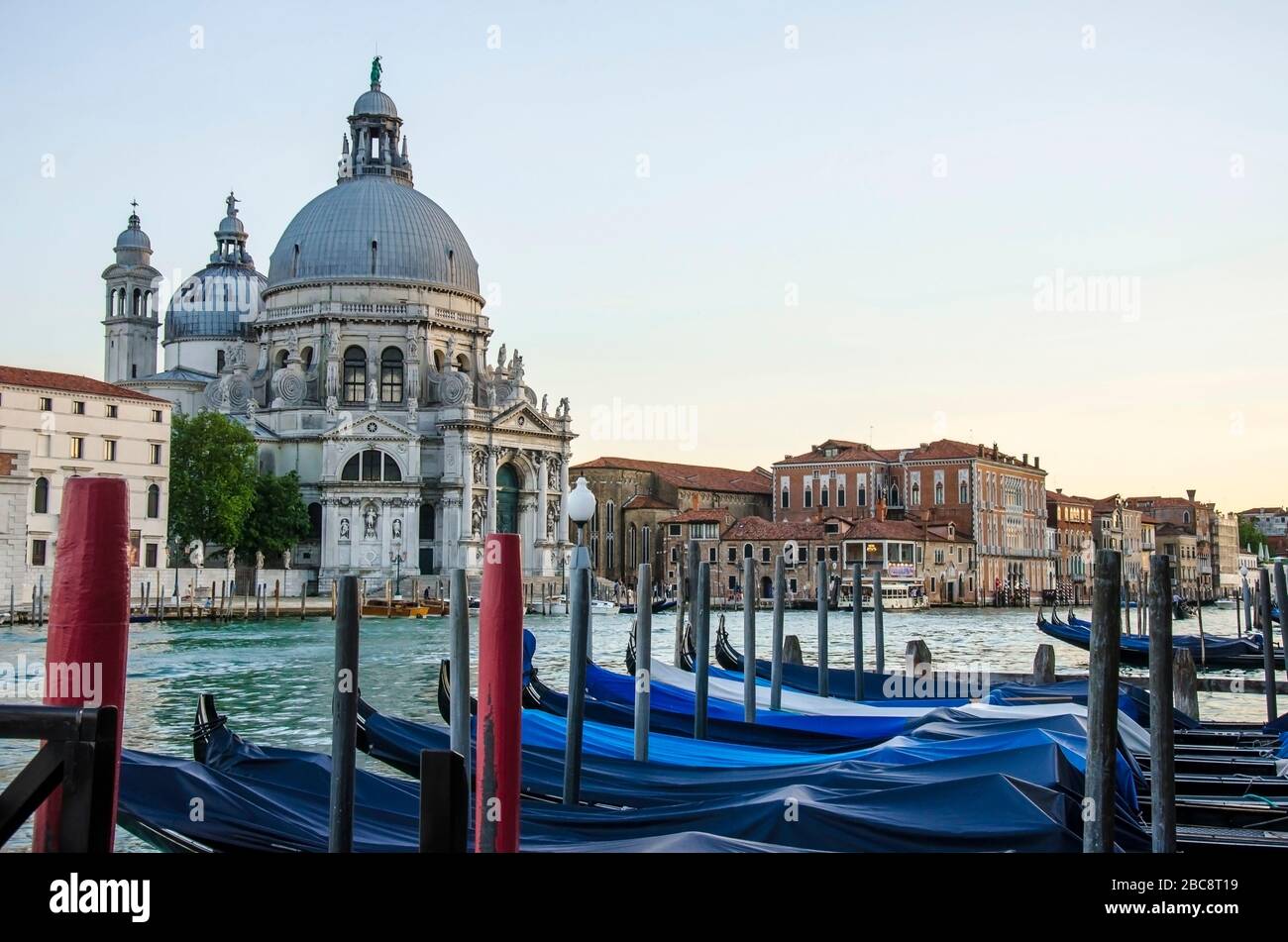 Vista delle gondole tradizionali sul famoso Canal Grande con la storica Basilica di Santa Maria della Salute sullo sfondo di Venezia Foto Stock