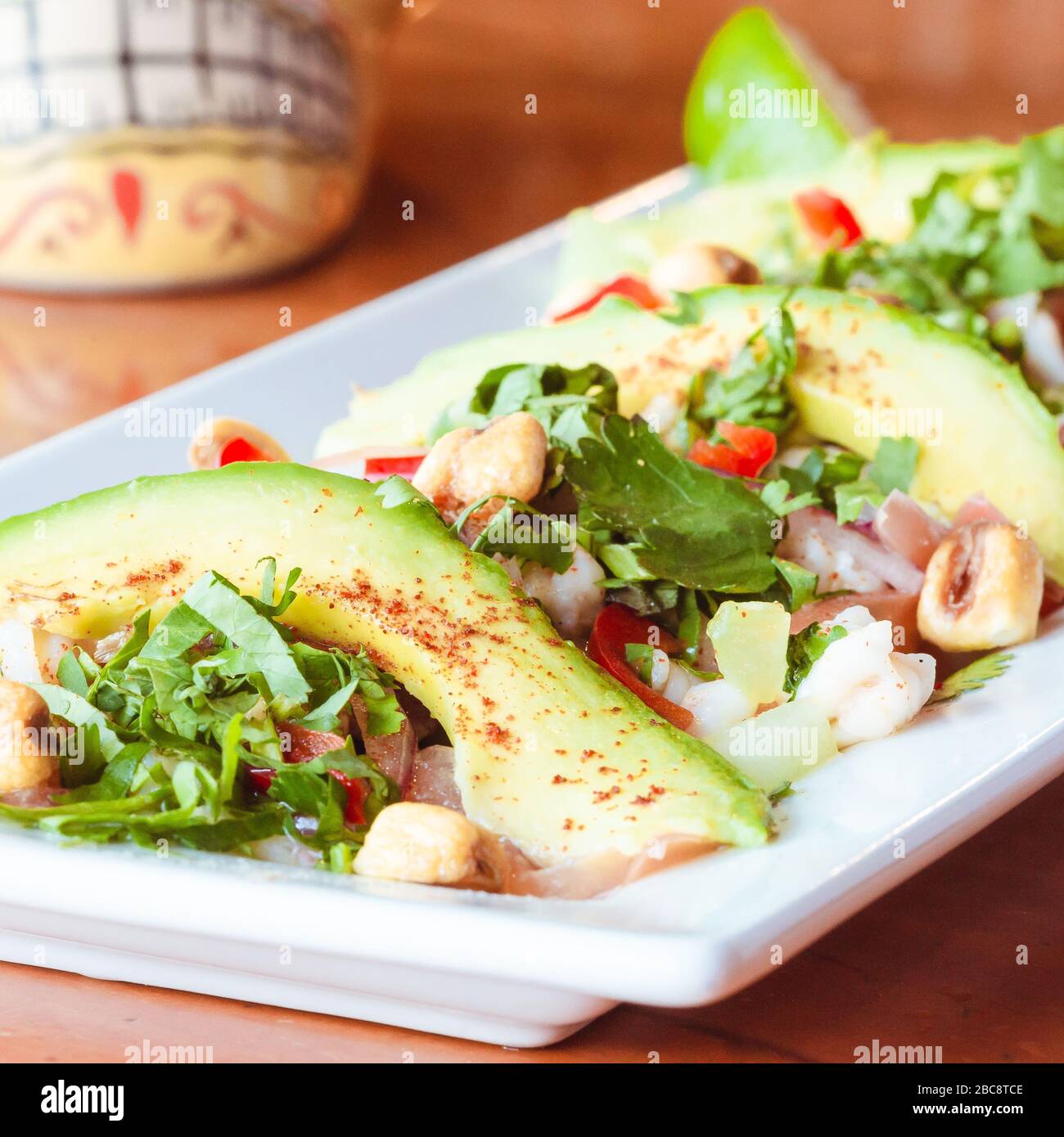 Tradizionale piatto di avocado ceviche messicano su superficie di legno lucido chiaro in ristorante messicano con tradizionale bevanda di ibisco messicano con dia de l Foto Stock