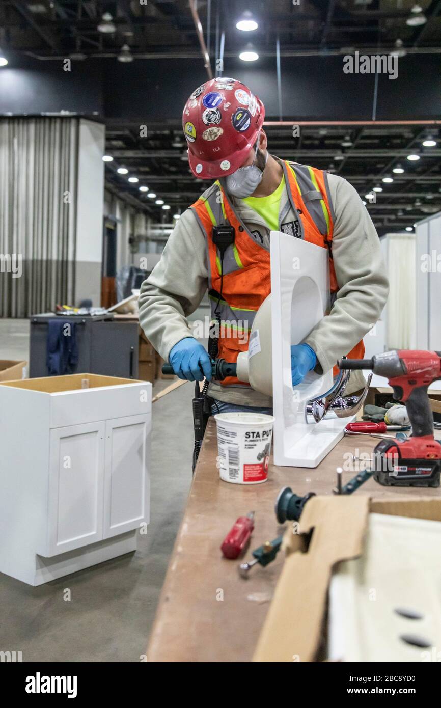 Detroit, Michigan, Stati Uniti. 2nd Apr, 2020. I lavoratori costruiscono un ospedale sul campo di emergenza presso il centro congressi TCF. L'ospedale di 1.000 posti letto si occuperà dei pazienti di Covid-19. Un idraulico mette insieme lavelli per stazioni di lavaggio a mano. Credito: Jim West/Alamy Live News Foto Stock