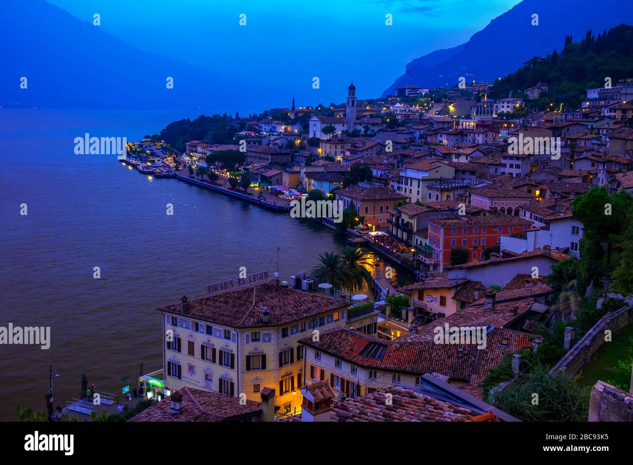 Passerella sul Lago di Garda con case, turisti e barche a Torbole, Italia Foto Stock