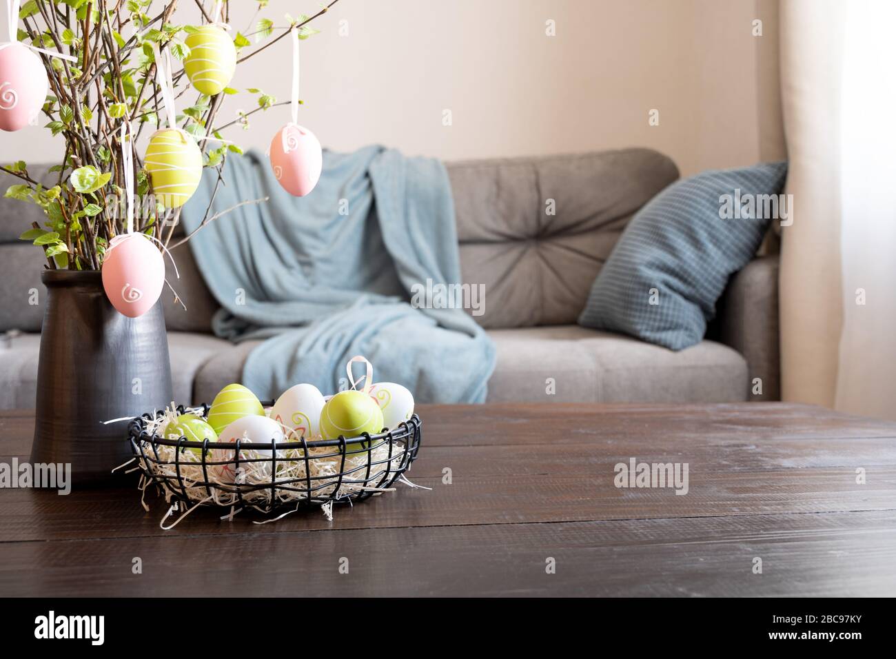 Interni primaverili con albero di Pasqua e vaso con uova colorate. Quarantena. Autoisolamento. Foto Stock