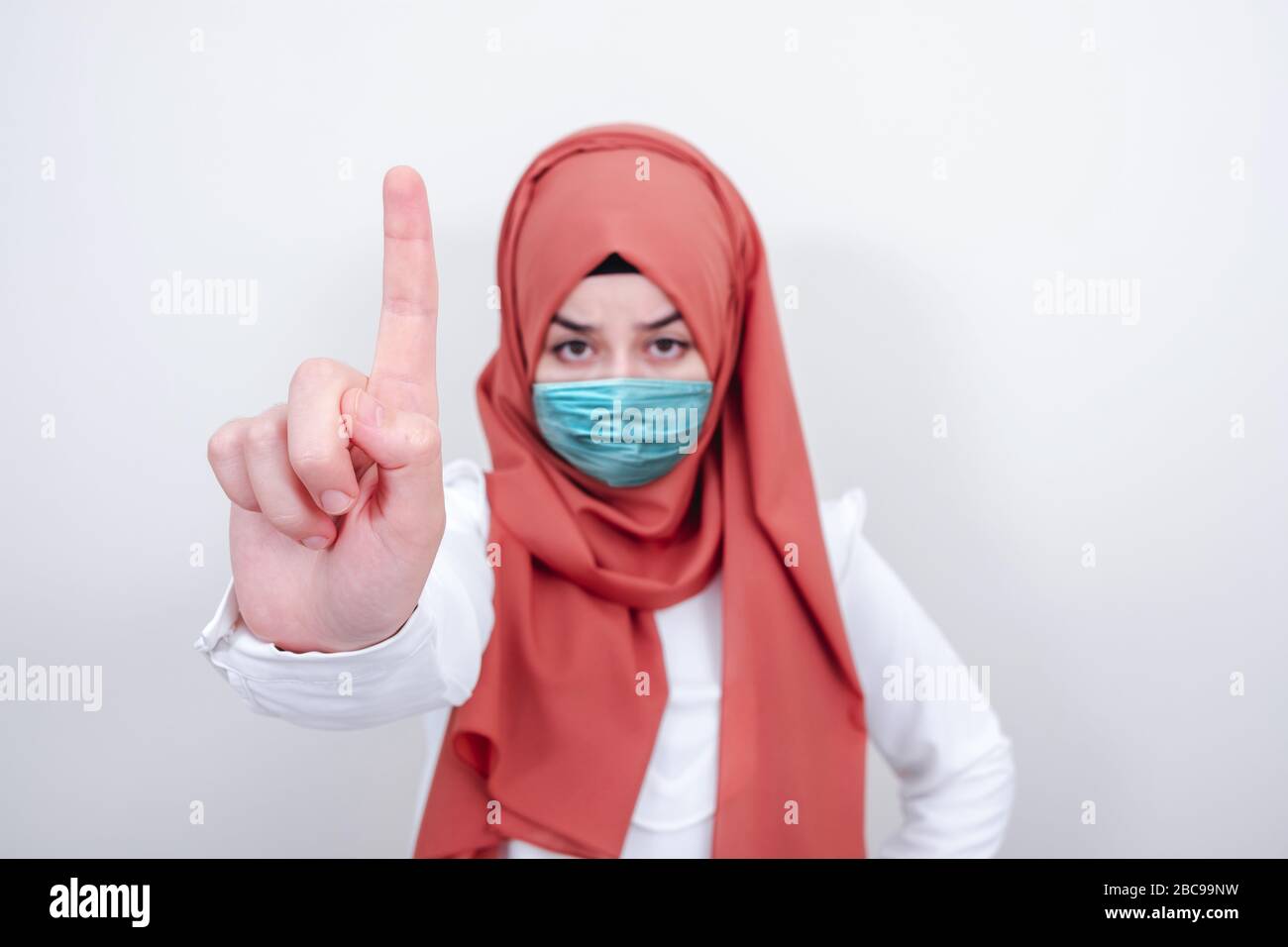 Ragazza musulmana che indossa una maschera chirurgica per la protezione. Donna hijab prendere una maschera per coronavirus o COVID-19 epidemia o pandemica Foto Stock