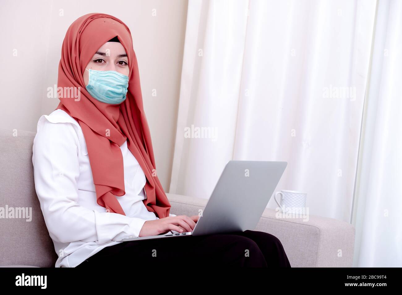 Ragazza musulmana che indossa una maschera chirurgica per la protezione. Donna hijab prendere una maschera per coronavirus o COVID-19 epidemia o pandemica Foto Stock